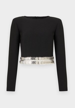 Melna garām piedurknēm blūze ar apaļu kakla izgriezumu, kurai apkārt ir spīdīga metāla apdare ap apakšmalu kā akcenta elements.