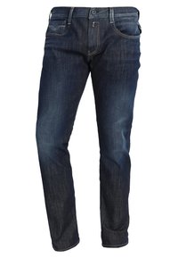 Mörkblå denimjeans med rak bendesign, fem fickor och synlig sömnad. Har dragkedja och knappstängning.
