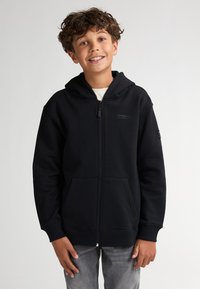 Haut à capuche zippé noir en mélange de coton doux, avec une poche frontale, des poignets côtelés et une capuche avec cordon de serrage. Détail du logo en accent.