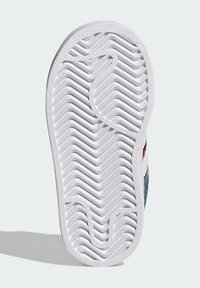 Podplat čevlja iz belega gumijastega materiala z reliefnim vzorcem cik-cak in valov, zasnovan za oprijem in vzdržljivost.