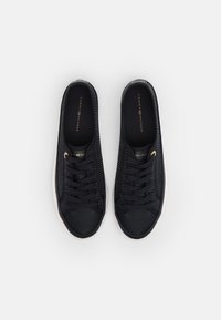 Černé plátěné tenisky s texturovaným svrškem, plochými tkaničkami a kulatou špičkou. Zlaté logo na stélce a bílá gumová podrážka.