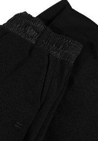 Zwarte fleecebroek met een elastische tailleband, met een gladde textuur en een licht gekreukt uiterlijk. Geen zichtbare patronen of hardware.