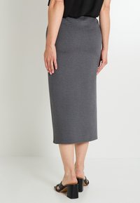 Jupe midi grise en tissu doux, à la coupe ajustée et droite. Caractérisée par un ourlet simple et un style minimaliste.