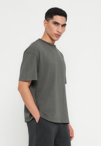 Czarna szara, oversize t-shirt z bawełny, z okrągłym dekoltem, krótkimi rękawami i luźnym krojem. Miękka tekstura z bocznymi rozcięciami.