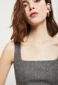 Grijze visgraatprint top met vierkante halslijn en brede straps. Heeft een gladde stoftextuur en subtiele stikdetails.