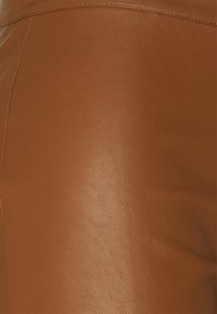 Tissu en cuir synthétique marron avec une texture lisse. Présente un design ajusté et un éclat subtil, affichant une surface uniforme sans motifs.