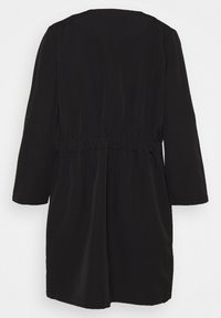 Black midi dress with long sleeves, elastic waist, smooth texture, and a simple cut. Back view showcases a relaxed, flowing silhouette.