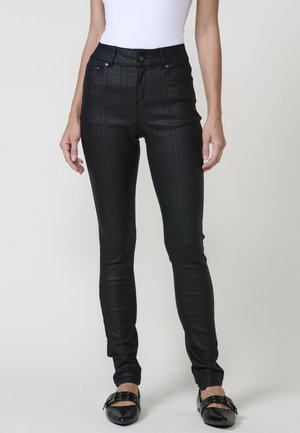 Jean skinny noir à carreaux, fabriqué en matériau léger, avec une taille haute, des poches avant et une finition lisse et texturée.