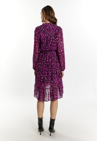 Paarse luipaardprint jurk van doorschijnende stof, met een laagjeszoom, een taille die is gecinched en lange mouwen. Gestyled met zwarte enkelbottines.