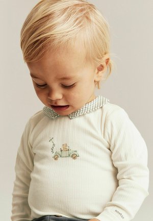 Hvid, ribstrikket langærmet skjorte med en grønternet krave. Har et lille broderet motiv af en bil og en bjørn.