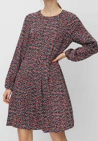 Černé šaty s dlouhými rukávy, zdobené barevným květinovým vzorem v červené, bílé a modré barvě. Rozšířený střih s kulatým výstřihem. Měkká textura látky.