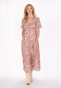 Rózsaszín paisley mintás maxi ruha, rövid ujjak, V-kivágás, áramló dizájn, könnyű anyag, krémszínű cowboy csizmával viselve.