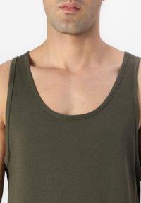 Olívazöld ujjatlan felső, puha anyagból készült, kerek nyakkivágással és széles pántokkal, sima textúrájú és fitted fazonú.