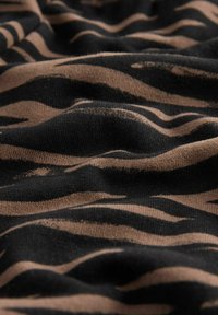 BOMULDSSTOF med et bølget mønster af brune og sorte zebra-striber, der viser tekstur og dybde i folderne.