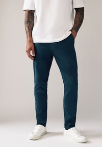 Seafoamgroene chino's met een slim fit, gemaakt van een zachte katoenmengstof; gecombineerd met een wit T-shirt en witte sneakers.