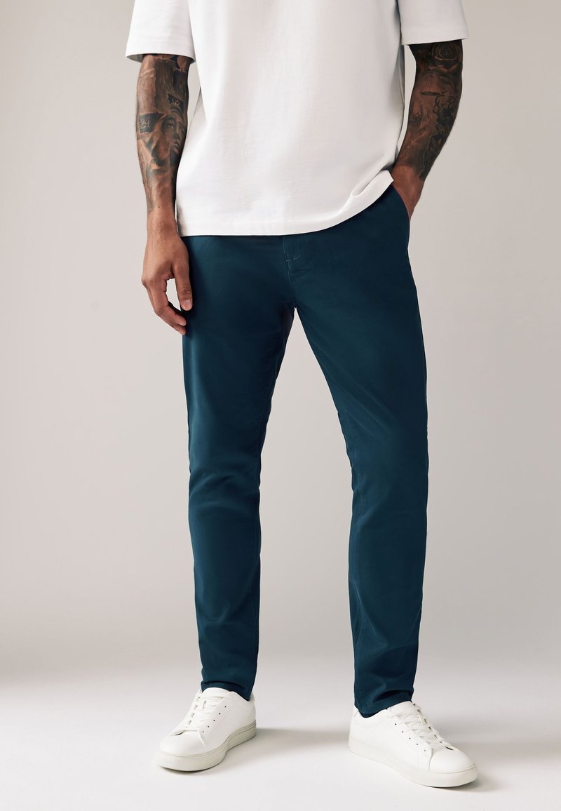 Seafoamgroene chino's met een slim fit, gemaakt van een zachte katoenmengstof; gecombineerd met een wit T-shirt en witte sneakers.