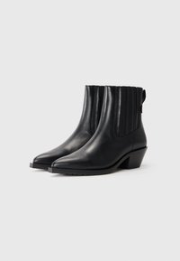 Botas de cuero negro hasta el tobillo con punta afilada, paneles acanalados en el tubo y tacón cuadrado. Suela de goma texturizada para mayor adherencia.