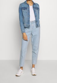 Vaaleansininen farkkutakki etutaskuilla, yhdistettynä vaaleansinisiin korkea vyötäröiseen farkkuihin ja valkoisiin tennareihin. Rentoa, istuvaa muotoilua.