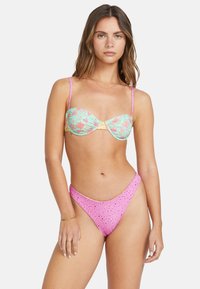Färgglad tvådelad bikini med en pastellgrön blommönstrad topp med justerbara remmar och en rosa botten med utskärningar.