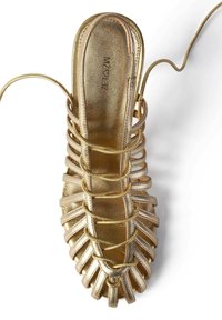 Sandală metalică aurie cu toc înalt, având un design cu bretele, vârful închis și o dantelare intricate. Textură netedă cu un finisaj lucios.