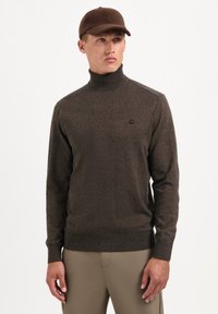Bruine coltrui gemaakt van getextureerde brei stof, met een aansluitend ontwerp en een klein logo accent op de borst.