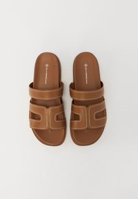 Brune glidesandaler med to justerbare stropper og sydde detaljer. Glatt syntetisk materiale, flat såle og et moderne design.
