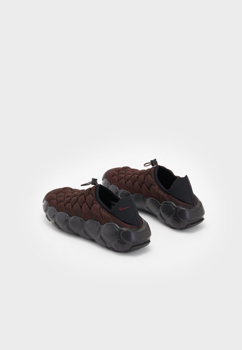 Buty Nike z teksturowaną, bordową siateczką na cholewce i grubą czarną gumową podeszwą. Posiadają konstrukcję typu slip-on z pętelką z tyłu.