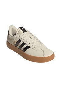 Beige Adidas sneakers med svarta ränder, gummisulor, snörningar knutna, och Adidas-logotyp på tungan och sidan, vinklad åt höger.