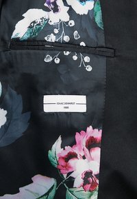 Czarna tkanina z kwiatowym wzorem w różu i bieli, z metką "ISAAC DEWHIRST 1880" wszytą w podszewkę.