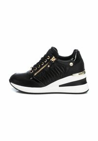Las zapatillas negras presentan un diseño acolchado, acentos metálicos, cremallera lateral y una suela de cuña blanca gruesa con una franja negra.