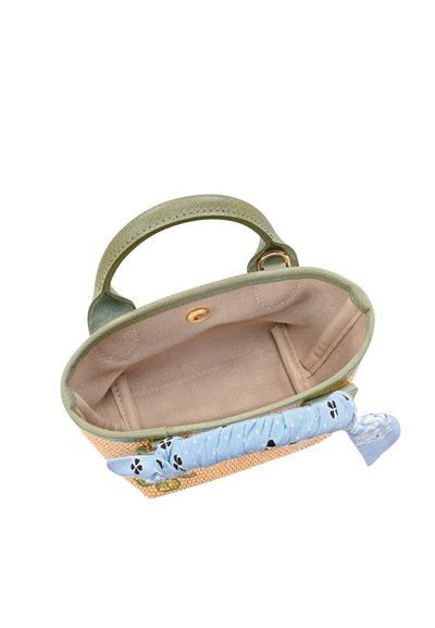 Small open woven handbag with green handles, beige fabric interior, and a blue patterned fabric tied around the zipper.