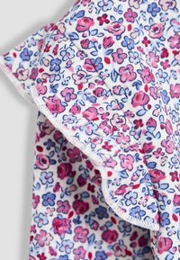 Blumenmusterstoff mit pinken, roten und blauen Blumen auf einem weißen Hintergrund; hat VOLANTKANTEN und eine weiche, strukturierte Oberfläche.