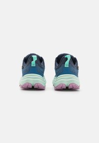 Miesten juoksukengät, joissa on laivastonsininen yläosa, mintunvihreä välipohja ja violetti ulkopohja. Kenkässä on teksturoidut materiaalit ja kantapäässä vedettävä lenkki.