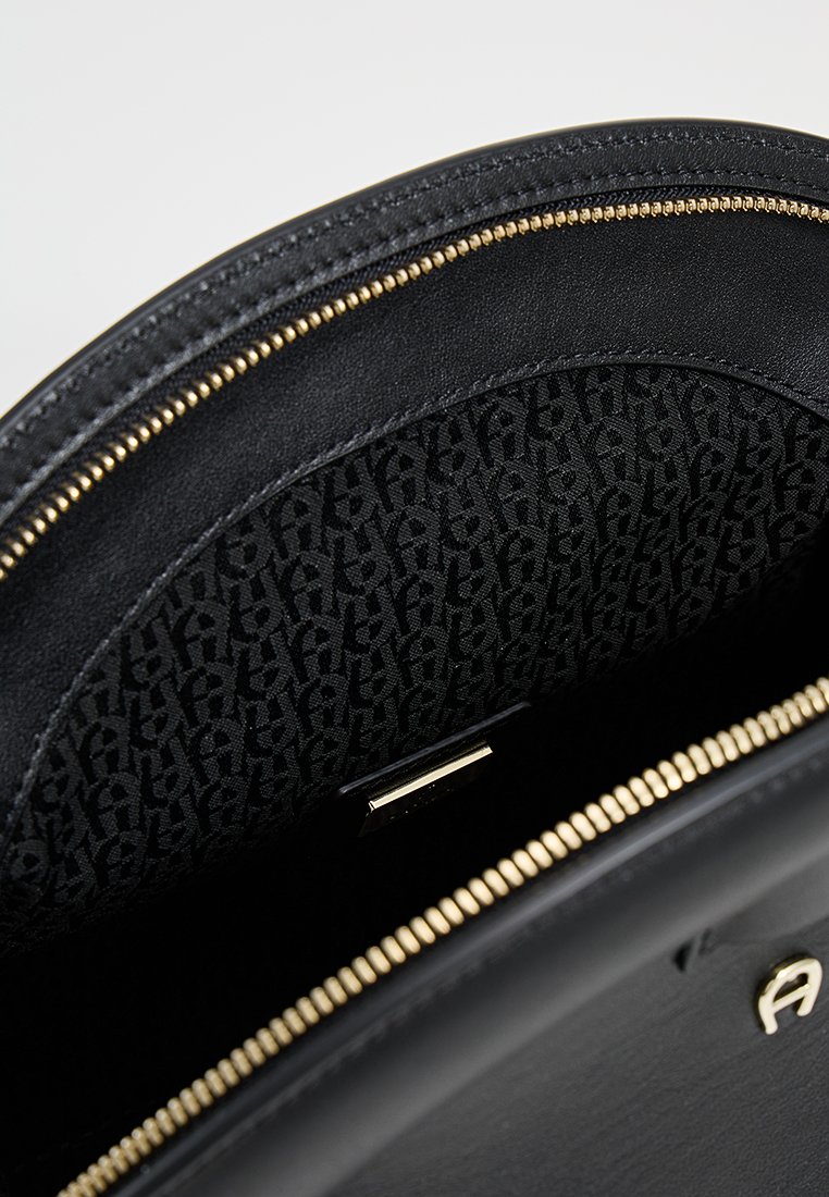 Schwarze Leder-Handtasche mit einem goldenen Reißverschluss, ausgestattet mit einem gemusterten schwarzen Innenfutter. Glatte Textur und runde Form. Goldene Hardware-Details.