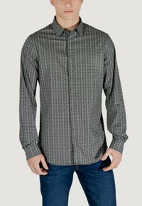 Camicia a maniche lunghe con bottoni in un motivo geometrico bianco e nero, caratterizzata da colletto aperto e polsini aderenti, realizzata in tessuto leggero.