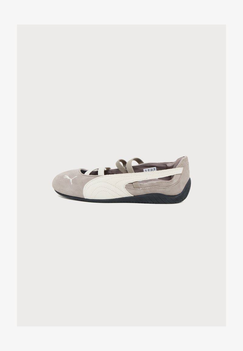 Baskets légères marron clair et blanches sans lacets avec des brides élastiques et une semelle noire texturée, vues de profil sur un fond blanc uni.