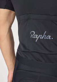 Maillot de cyclisme noir à coupe ajustée, arborant le logo "Rapha." emblématique dans une teinte plus claire, avec un tissu lisse et texturé.