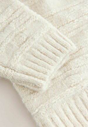 Nahaufnahme von einem kräftigen, cremigen Strickstoff mit geripptem Muster und subtiler Textur, die Wärme und Weichheit betont.