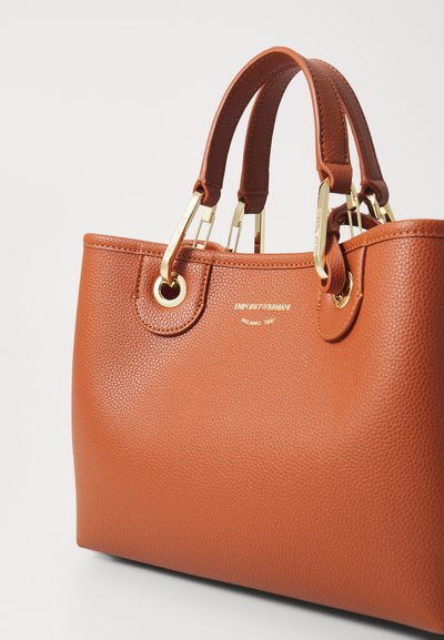 Sac à main en cuir marron avec une finition texturée, accents en matériel doré, doubles poignées et détail de logo à l'avant.