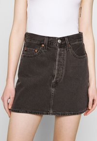 Denim skirt in donkergrijs, met een sluiting met knopen aan de voorkant, twee voorzakken en contrasterende stiksels. Rechte snit, halverwege de bovenbenen.