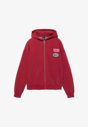 Červená mikina na zips s kapucňou, prednými vreckami a dvoma nášivkami na hrudi s nápisom "West Garage NYC" a "WG91".