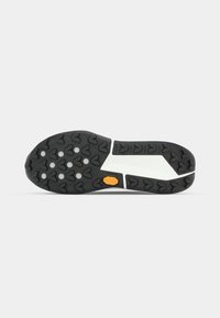 Schwarzer Gummisohlen mit herzförmigen Profilen, weiße Zwischensohle und einem kleinen gelben Vibram-Logo in der Mitte.