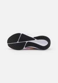 Semelle de chaussure avec une bande de roulement en caoutchouc noir et une semelle intermédiaire blanche, avec des motifs de grip géométriques et un petit logo swoosh embossé sur le côté droit.