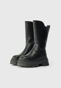 Botas de montaria de couro preto até ao joelho, com bico arredondado, sola de borracha espessa e detalhes em relevo na parte de trás. Apresentam um design elegante e moderno.