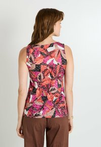 Top sin mangas con vibrantes patrones florales en rosa, blanco y negro. Hecho de una tela ligera y texturizada, con un diseño ajustado en la parte posterior.