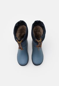 Bottes en caoutchouc bleues avec une douce doublure en fourrure marron, upper marine et lacets marron. Le design comprend une pointe arrondie et une semelle texturée pour une meilleure adhérence.