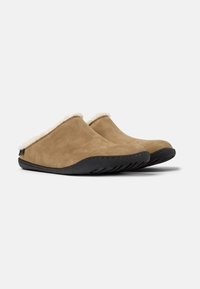 Bruna mockasiner i mocka med en mjuk vit insida, med en svart gummisul och släta kanter för en minimalistisk design.