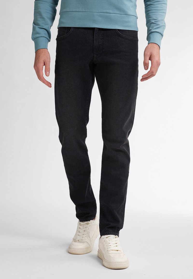 Czarne jeansy denimowe o dopasowanym kroju, z pięcioma kieszeniami i subtelnymi detalami w szwie, zestawione z białymi trampkami i jasnoniebieską bluzą.