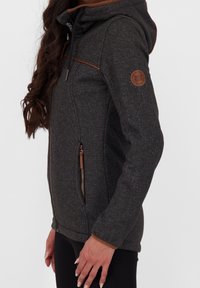 Tmavě šedá mikina s kapucí vyrobená z texturované tkaniny, s kontrastními světlými hnědými akcenty, zipovou kapsou a logem na rukávu.