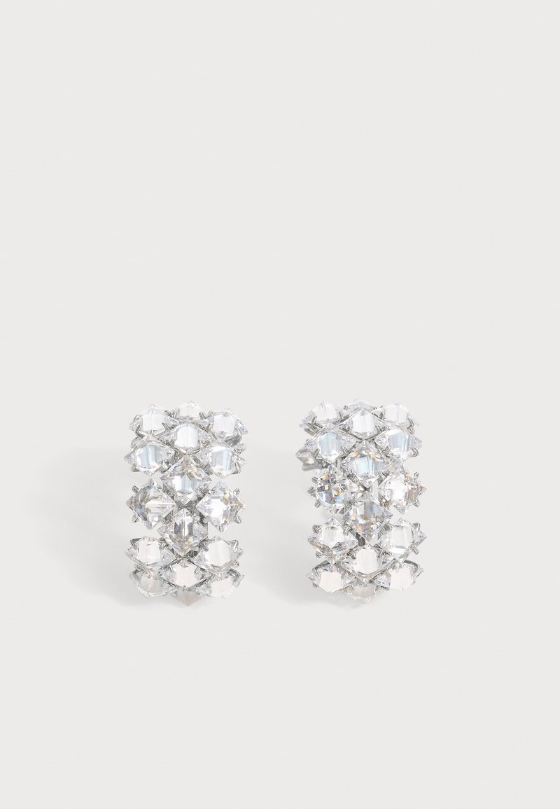Paire de boucles d'oreilles ton argent avec plusieurs cristaux clairs facettés disposés en motif géométrique.